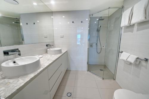 a white bathroom with a sink and a shower at Belise Apartments in Brisbane