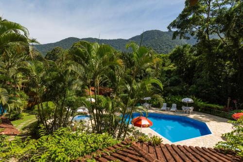 a resort with a pool and mountains in the background at Pousada Pé da Mata Maresias in Maresias