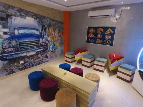 a room with a car painting on the wall and stools at M Inn in Coimbatore