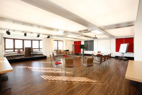 a large room with chairs and tables and a flat screen tv at Hotel Schönbuch in Pliezhausen