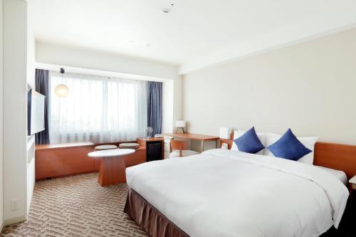 a hotel room with a large bed with blue pillows at Keio Plaza Hotel Sapporo in Sapporo