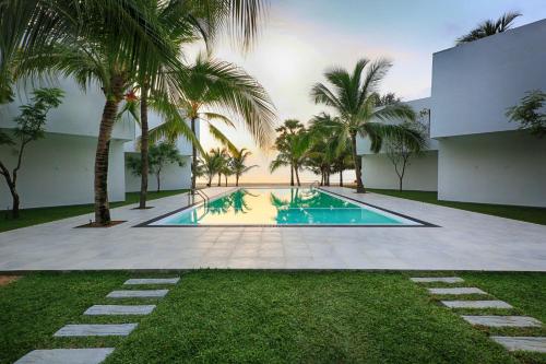 a swimming pool with palm trees in front of a building at Arugambay Roccos in Arugam Bay