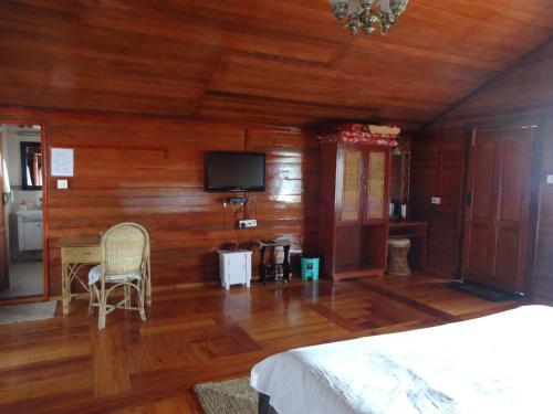 1 dormitorio con paredes de madera, 1 cama y TV en Surya Holidays Kodaikanal, en Kodaikanal
