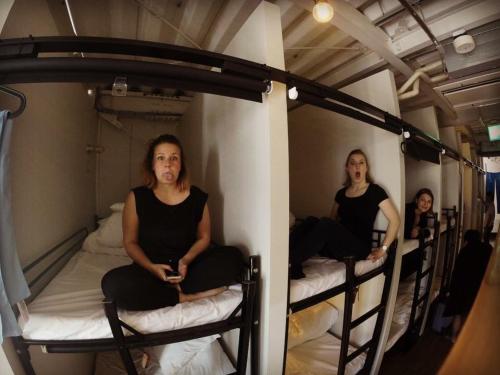 two women sitting on bunk beds in a room at Chillulu Hostel in Yokohama