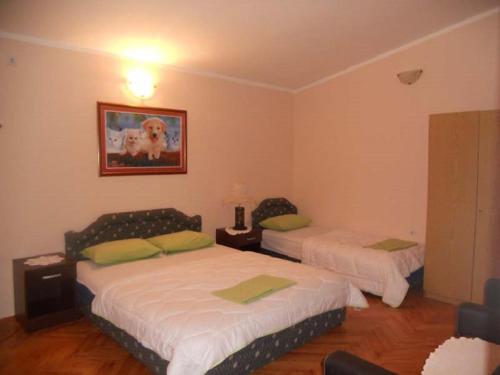 a bedroom with two beds and a dog picture on the wall at Apartment Stana in Petrovac na Moru