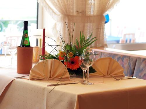 a table with a wine glass and a vase of flowers at Moselstern-Hotel "Weinhaus Fuhrmann" in Ellenz-Poltersdorf