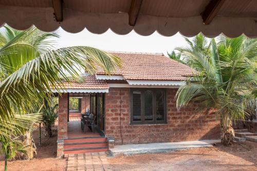 a small brick house with palm trees in front of it at Beachfront Villas in Ganpatipule