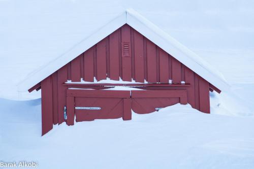 a red barn with snow on the roof at Abisko Guesthouse & Activities in Abisko