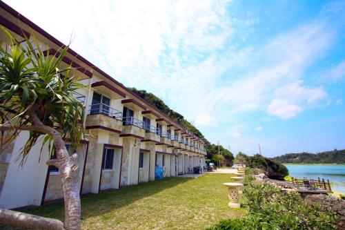 a building with a grass yard next to a body of water at Hotel Oceans Nakijin in Nakijin