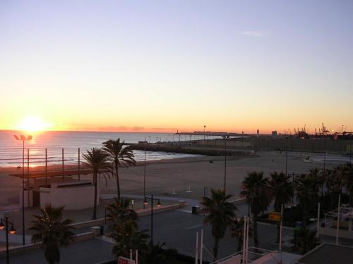 a sunset over a beach with palm trees and the ocean at El Globo in Valencia