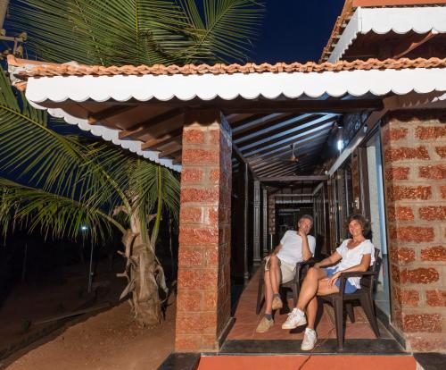 two people sitting on the porch of a house at Beachfront Villas in Ganpatipule