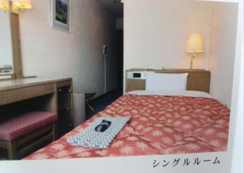 a hotel room with a bed with a red comforter at Asahi Century Hotel in Minami Alps