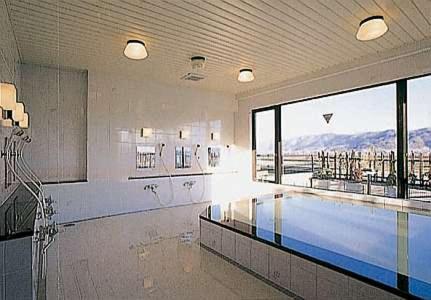 a swimming pool in a building with a large window at Asahi Century Hotel in Minami Alps