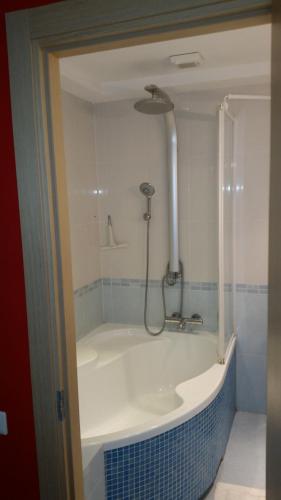 a bath tub with a shower in a bathroom at Family Apartment Nida in Nida