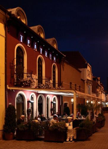 a group of people standing outside of a building at night at Teátrum Boutique Hotel in Győr