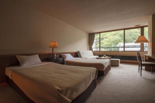 een hotelkamer met 2 bedden en een raam bij Nakamurakan in Takayama
