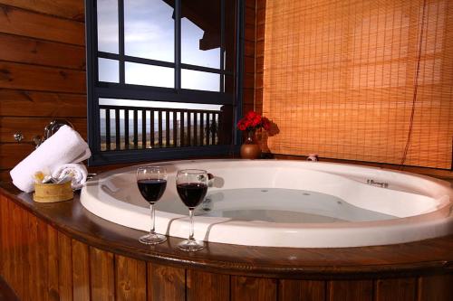 two glasses of wine sitting in a bath tub at Cabin Eretz Ha-Kineret in Had Nes
