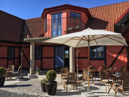 um pátio com uma mesa e um guarda-chuva em frente a um edifício em Villa Hasselbacken em Simrishamn