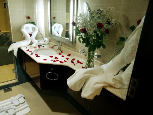 a bathroom with a mirror, a sink, and a bath tub at Concorde Hotel - Fujairah in Fujairah