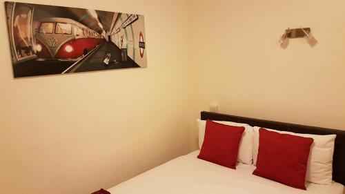 a bedroom with a bed with red pillows and a painting at Westpoint Hotel in London