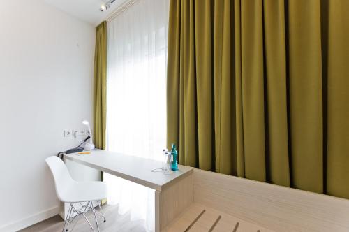 a room with a desk and a window with green curtains at Super 8 Freiburg in Freiburg im Breisgau