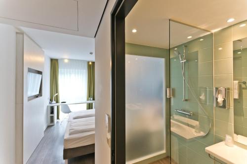a bathroom with a shower and a bed in a room at Super 8 Freiburg in Freiburg im Breisgau