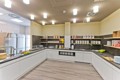 a large kitchen with white cabinets and stainless steel appliances at Super 8 Freiburg in Freiburg im Breisgau