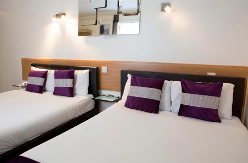 two beds in a room with purple and white pillows at Westpoint Hotel in London