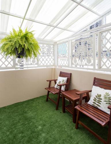two chairs and a plant in a room with windows at The Lek Aree in Bangkok