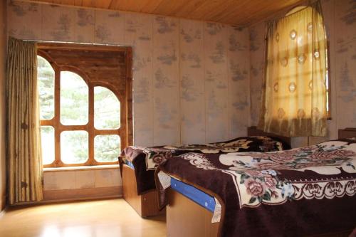 two beds in a room with two windows at Hotel Tusheti in Omalo