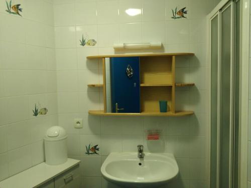 a white bathroom with a sink and a toilet at Gîte Le Clos des Pins in Colleville-sur-Mer