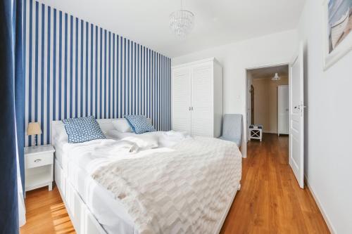 a bedroom with a large white bed with blue pillows at Apartamenty Sun & Snow Gdańsk Bursztynowa in Gdańsk