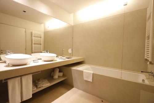 a bathroom with two sinks and a tub and a mirror at Montebelo Vista Alegre Ílhavo Hotel in Ílhavo