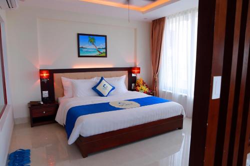 a bedroom with a large bed with blue and white sheets at Blue Wave Hotel in Cửa Lò