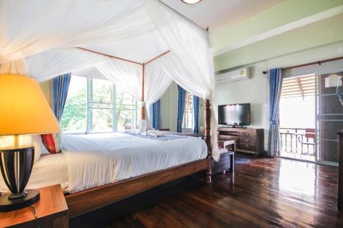 um quarto com uma cama de dossel e uma televisão em Changmoi House (Little Village) em Chiang Mai
