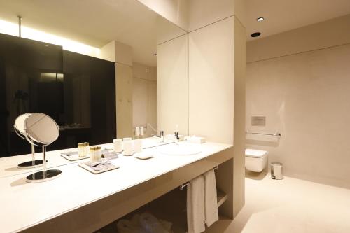 a bathroom with a sink and a mirror and a toilet at Montebelo Vista Alegre Ílhavo Hotel in Ílhavo