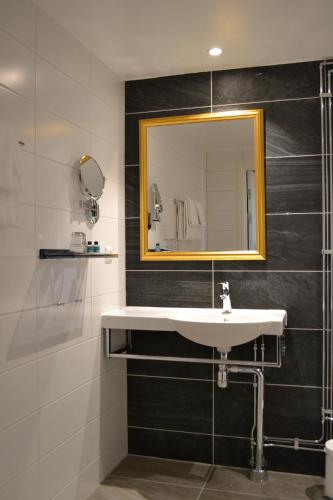 La salle de bains est pourvue d'un lavabo et d'un miroir. dans l'établissement Vänerport Stadshotell i Mariestad, à Mariestad