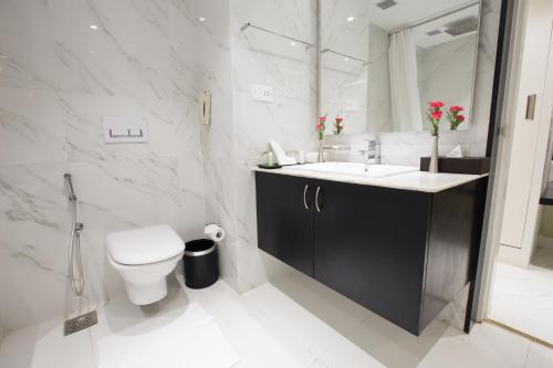 a white bathroom with a toilet and a sink at M Inn in Coimbatore