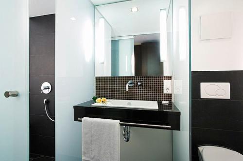 ein Bad mit einem Waschbecken und einem Spiegel in der Unterkunft Hotel Garni Krone in Radolfzell am Bodensee