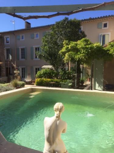 une statue d'une femme assise dans une piscine dans l'établissement O'palmier Caché, à Saint-Marcel