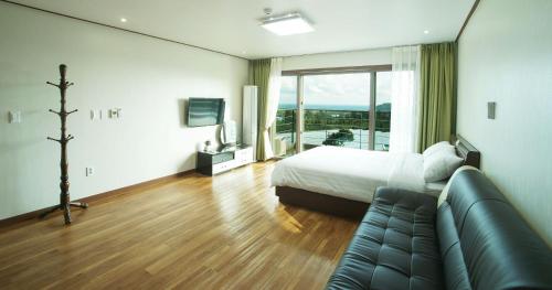 une chambre d'hôtel avec un lit et un canapé dans l'établissement Oasis Pension, à Seogwipo