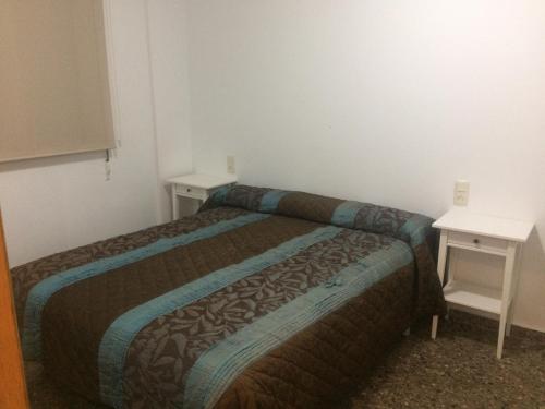Apartamento Abadia Teruel في تيرويل: غرفة نوم صغيرة بها سرير وطاولتين