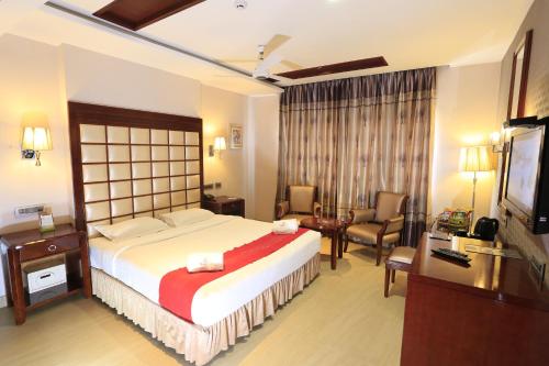 a hotel room with a large bed and a desk at Hotel Apple Ttree in Tirunelveli