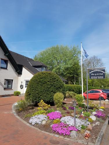 a garden with flowers and a sign in front of a house at Hus op de Diek in Sankt Peter-Ording