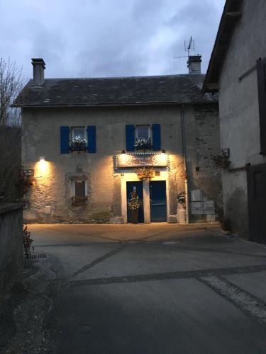 an old stone building with blue shutters on it at La Ferme de Gayri, chalet d'exception avec sauna et jacuzzi à 5 minutes de St-Lary Soulan in Vielle-Aure