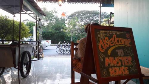 une personne assise sur une chaise à côté d'un panneau dans l'établissement Muster Guesthouse, à Phra Nakhon Si Ayutthaya