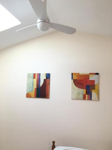 two paintings on a white wall with a ceiling fan at Boa Vista in São Bartolomeu de Messines