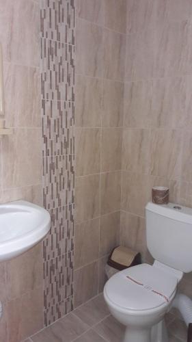 a bathroom with a white toilet and a sink at Dracena Guesthouse in Ravda