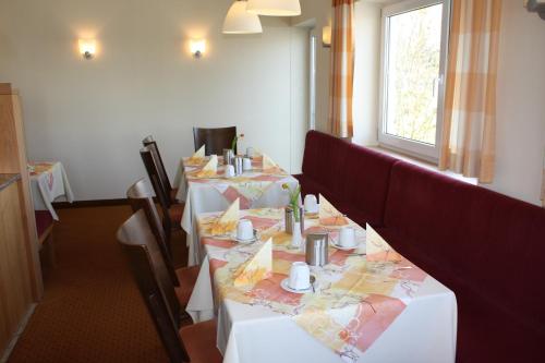 a dining room with white tables and chairs and a window at Pension Geno in Geisenhausen