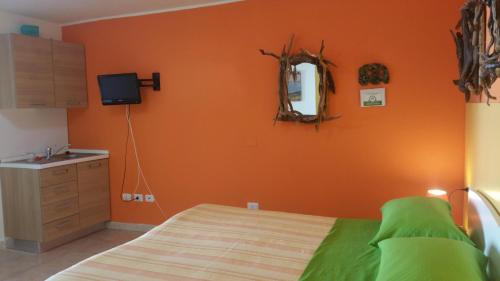 a bedroom with an orange wall with a bed and a mirror at Il Sogno di Alghero - Adults Only in Alghero